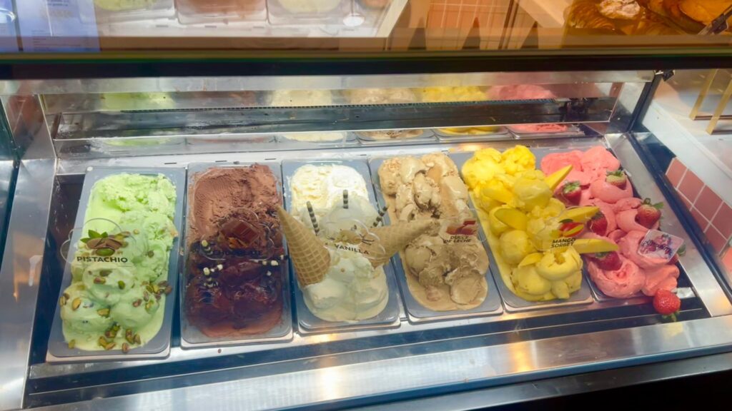 Gelato display case with pistachio, chocolate, vanilla, and fresh fruit flavors